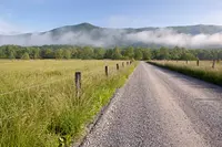 gravel road in Cades Cove in summer with mist over the mountains