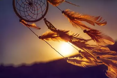 A dreamcatcher blowing in the wind at sunset.