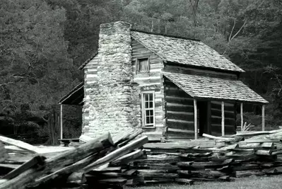 black and white image of historic Cades Cove cabin with split rail fence