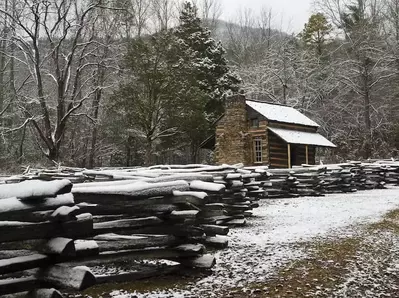 A snow covered cabin and fence in Cades Cove in the winter.