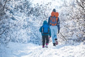 woman and child hiking in winter with winter clothes and backpacks